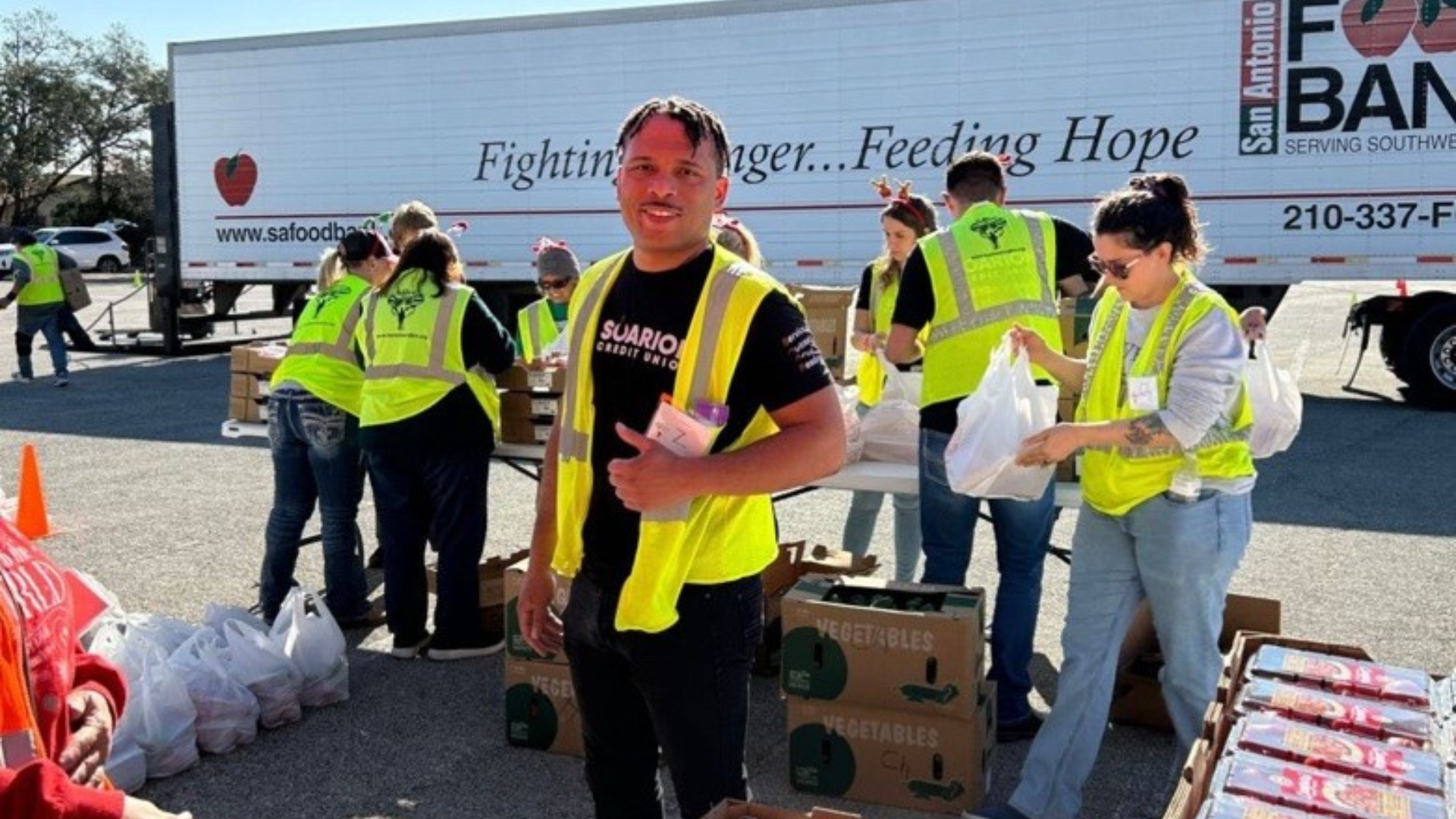 Soarion employee in a yellow vest at a volunteer event giving a thumbs up