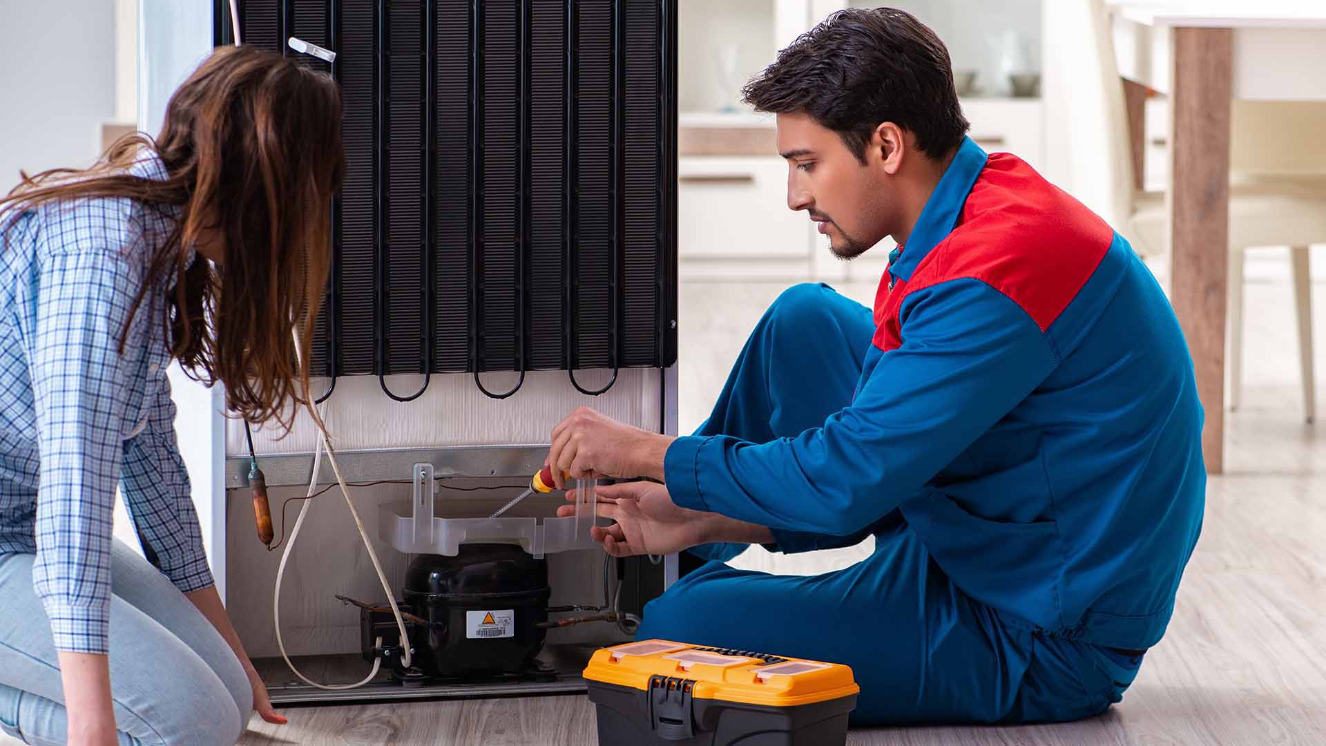 Repair man showing femaile owner issue with refrigerator