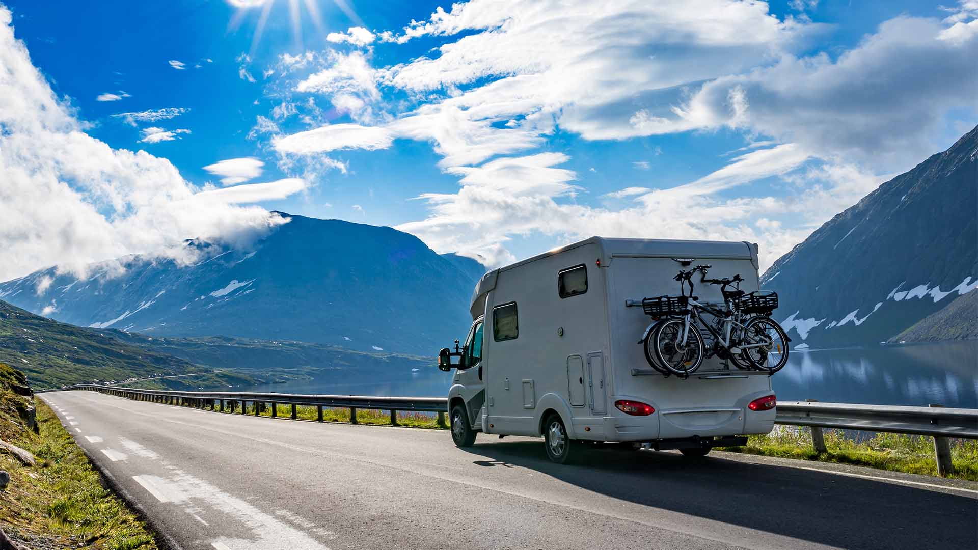 RV driving past mountains on a sunny day