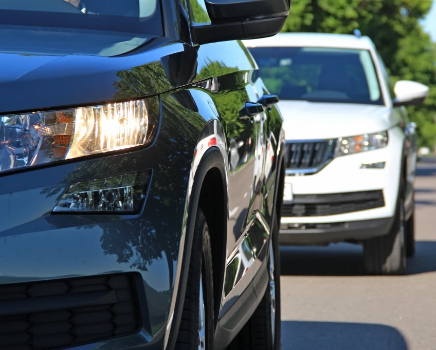 Vehicles driving in traffic with close-up view of car headlights and front grille