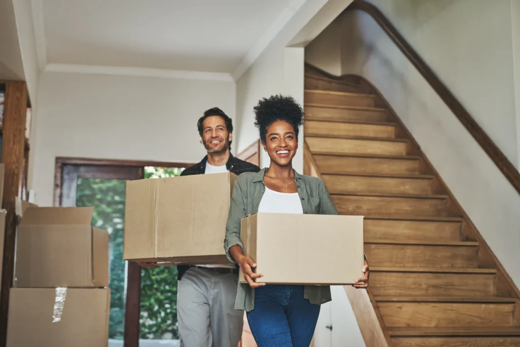 Couple carrying moving boxes into a new house
