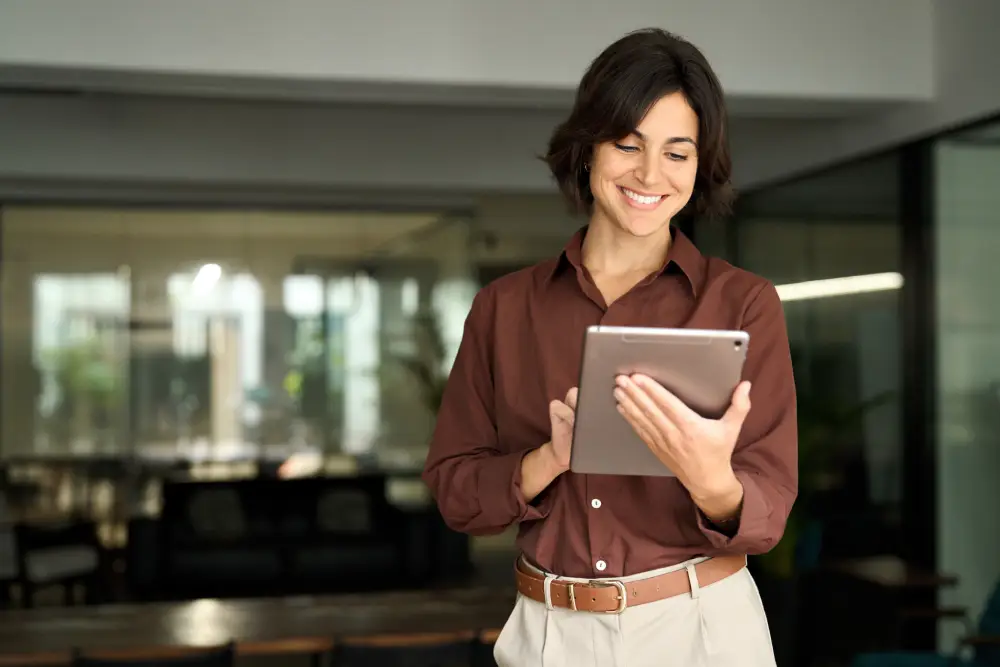 Woman smiling while using a tablet in a modern office