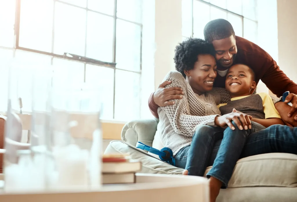 Family sharing a hug on a couch in a bright living room