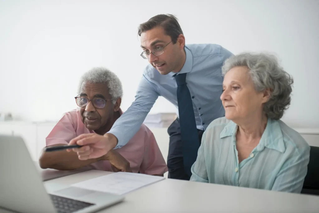Financial advisor helping an older couple review information on a laptop at a desk